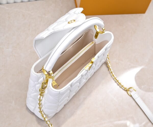 M23999 white. This Monogram embroidered floral design emerges in the elegant quilting, adding to the Louis Vuitton store's decoration style for the Capucines BB handbag. 33 x 19 x 9 cm